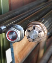 Machined propeller shaft ends with fitted nut and split-cone coupling, racked in the workshop